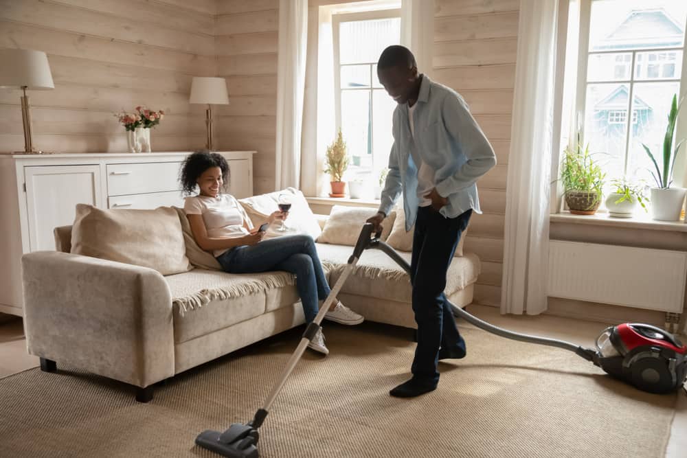 hombre limpiando casa mientras mujer sentada