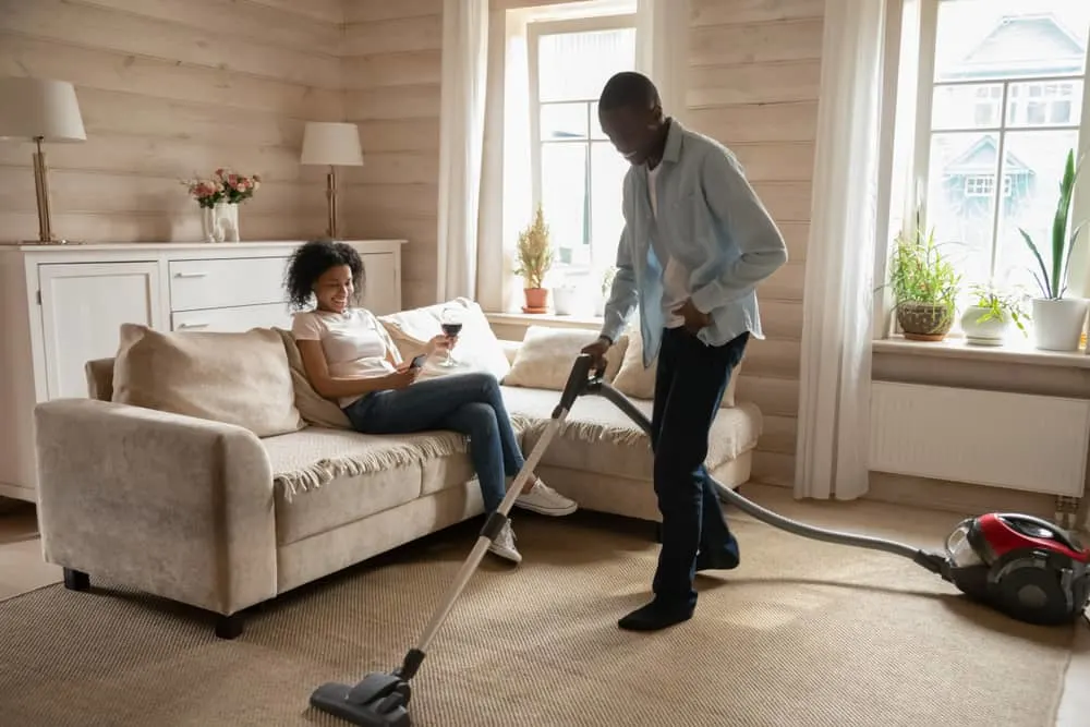 man cleaning house while woman sitting