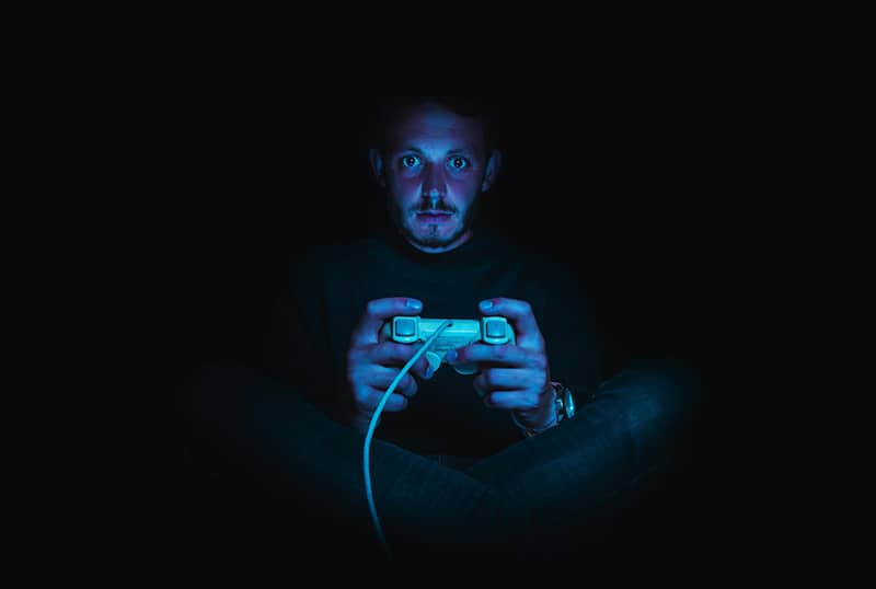 man holding game controller in the dark