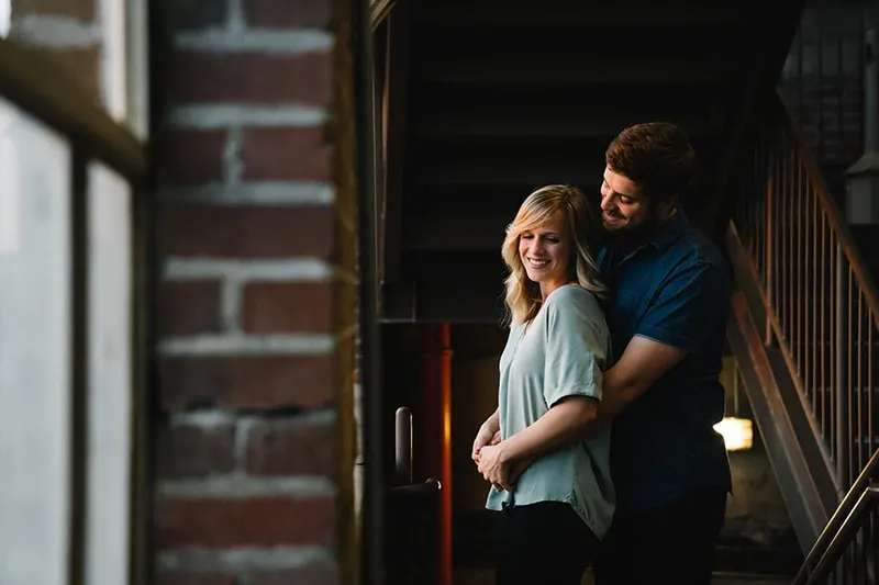man hugging woman from behind near stairs