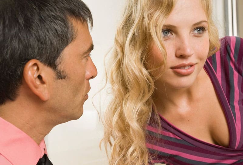 man looking at a woman with blonde curly hair 