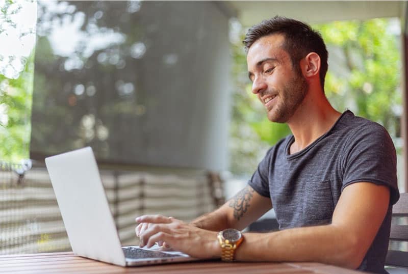 man on his laptop wearing gray shirt smiling