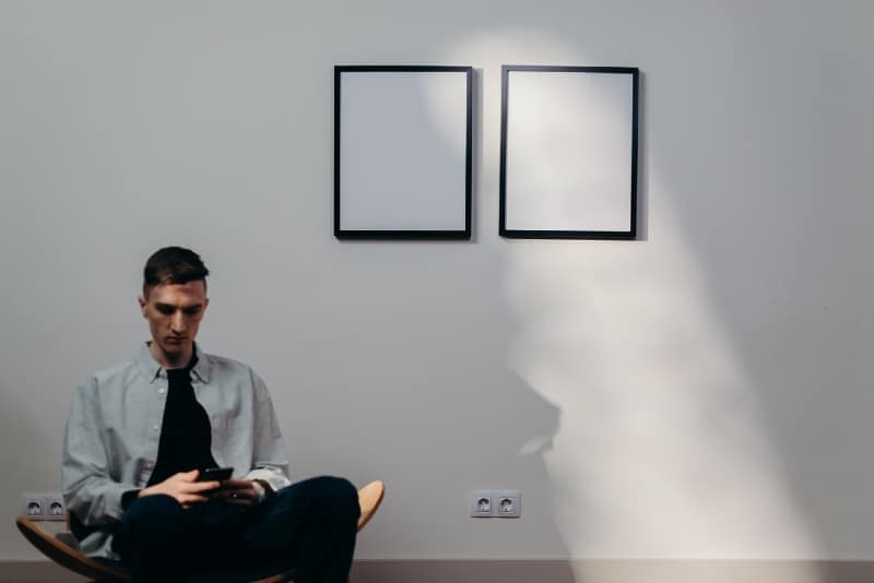 man sitting on chair and using smartphone