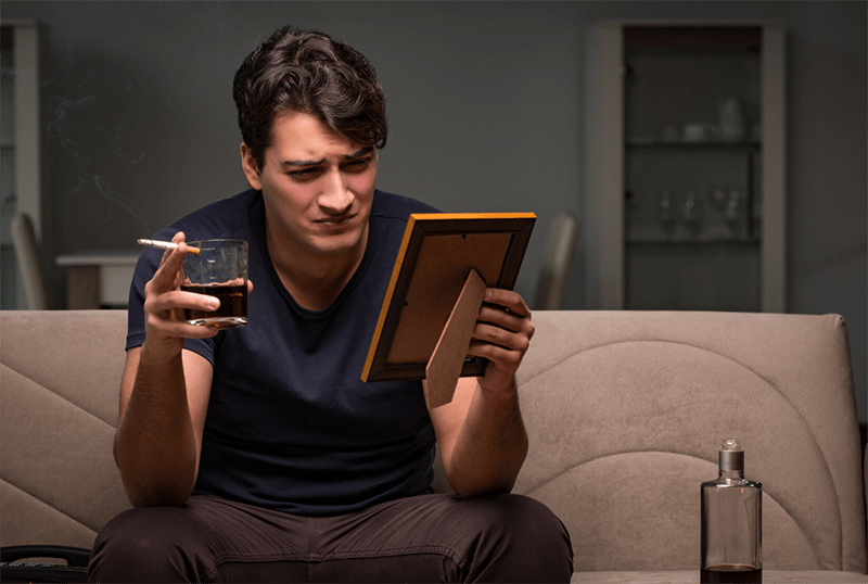 uomo che fuma sigarette e beve vino guardando una foto