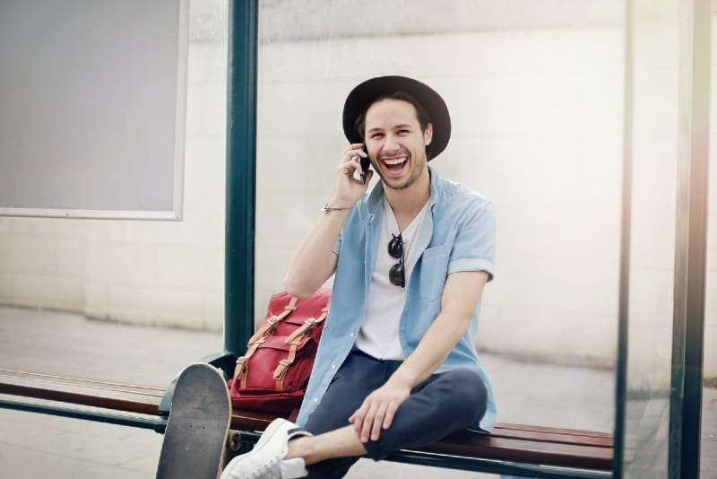 uomo che parla al telefono seduto su una panchina di legno