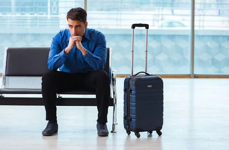 man waiting in the airport lounge with a luggage beside him