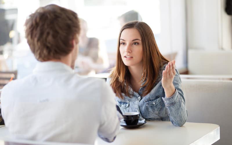 woman talking to man sitting in front of her at a table