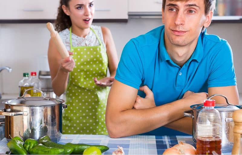 nagging woman wearing apron and holding a rolling pin to a husband wearing blue shirt