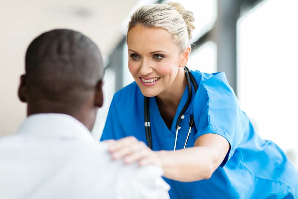 Nurse conforting patient sitting in front of her in an office