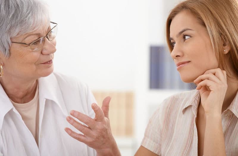 older woman talking to a younger woman listening and smiling