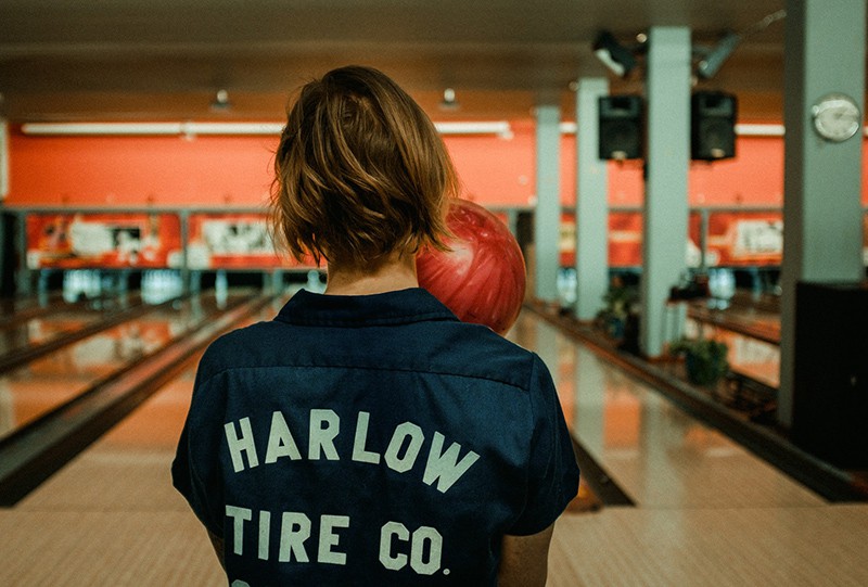 person holding bowling ball facing bowling pins