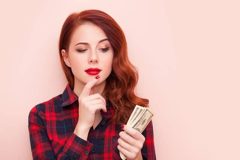 mulher de cabelo vermelho a segurar dinheiro