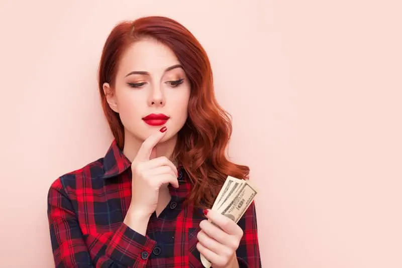 red haired woman holding money