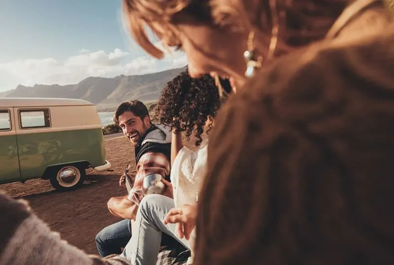 road trip with group of people with man playing guitar and a car from afar