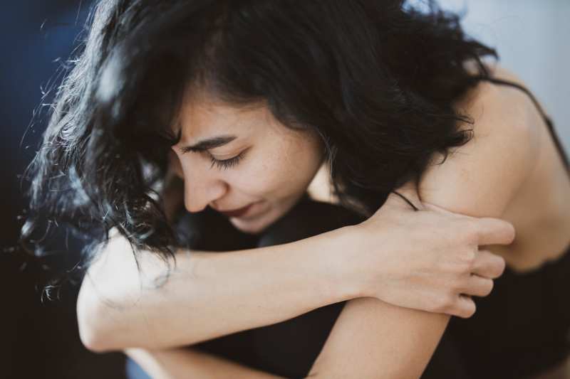 mujer triste de negro con la cabeza sobre las rodillas