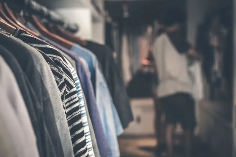 shallow focus photography of clothes in a closet with a person in a blurred distant