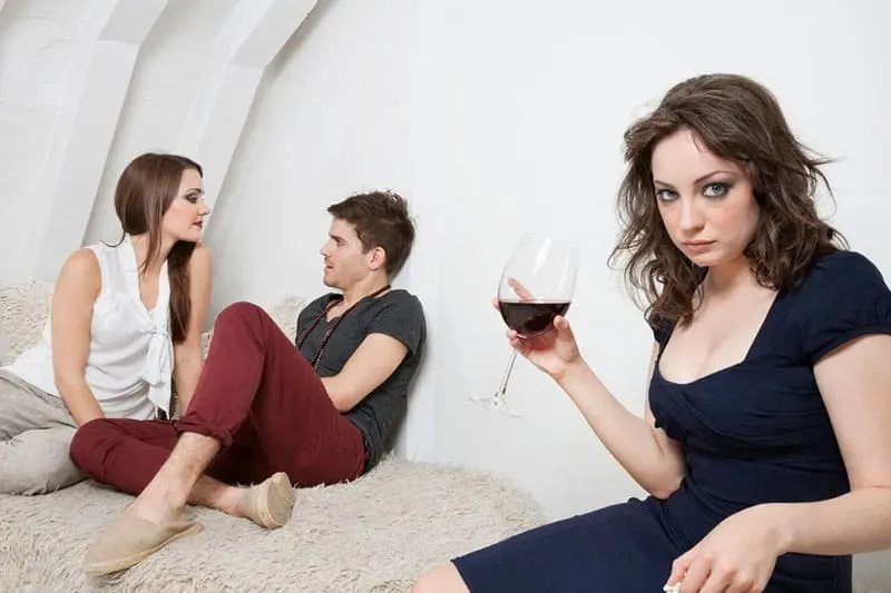 sweet couple near a woman holding a wine looking jealous