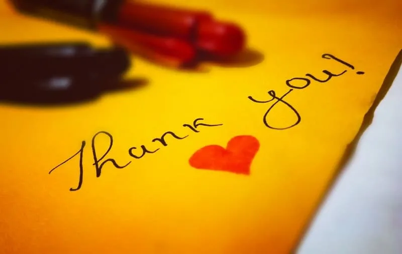 thank you heart text written in in yellow paper with ballpen place above the paper