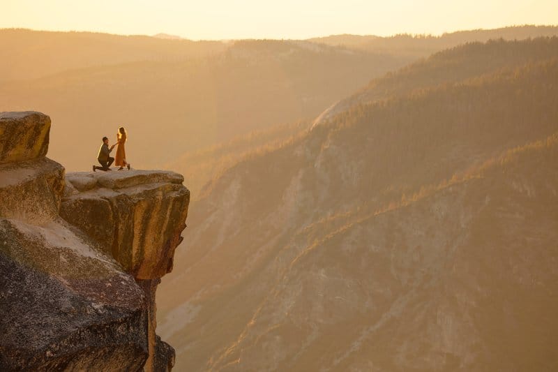 the guy proposes to the girl on a cliff of rock
