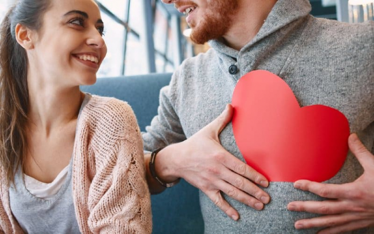 Man with red paper heart on chest near a happy woman