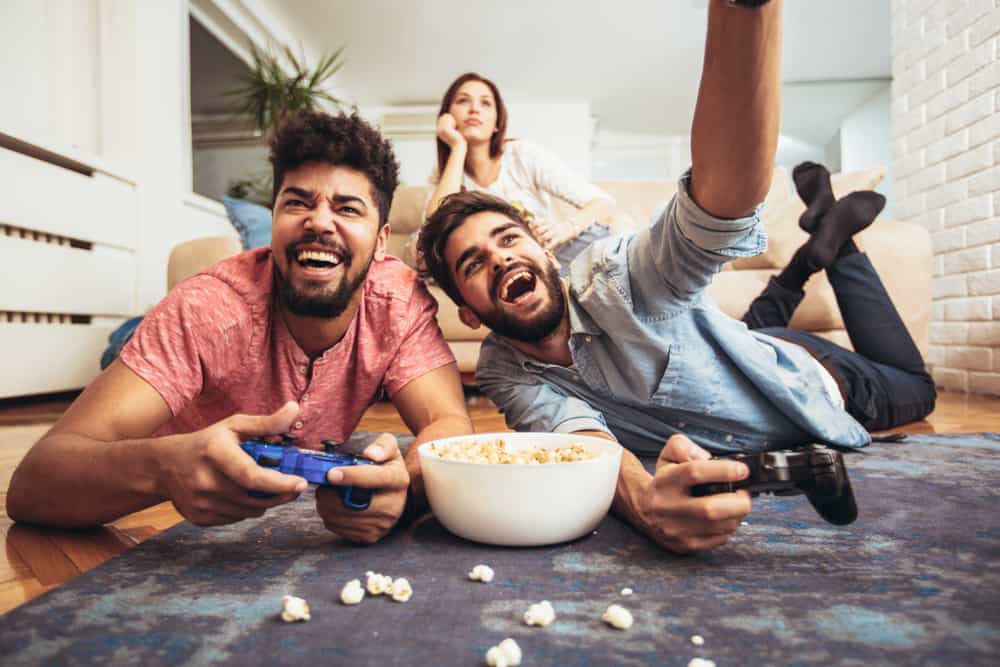 two guys playing video games with woman in background