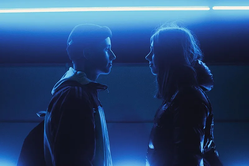 woman and man facing each other standing under blue lights