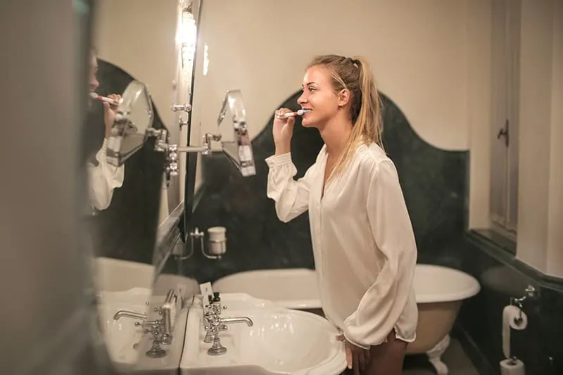 woman cleaning teeth in bathroom