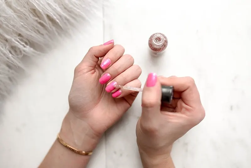 woman doing manicure with pink nail polish