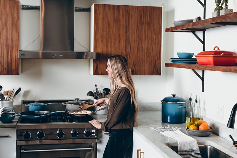 woman holding brown spatula while standing beside stove