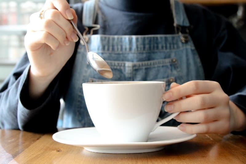 donna con in mano una tazza di caffè bianco in un bar