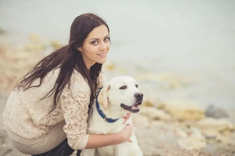 Young woman holding labrador dog
