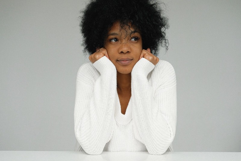portrait of woman in white sweater holding her chin