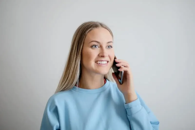 smiling woman in blue sweatshirt holding phone