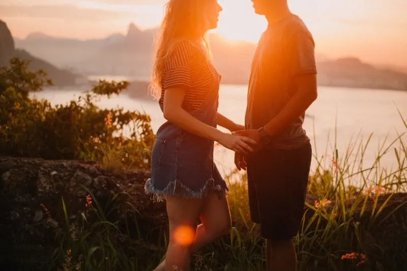 woman holding man's hand while standing outdoor during sunset