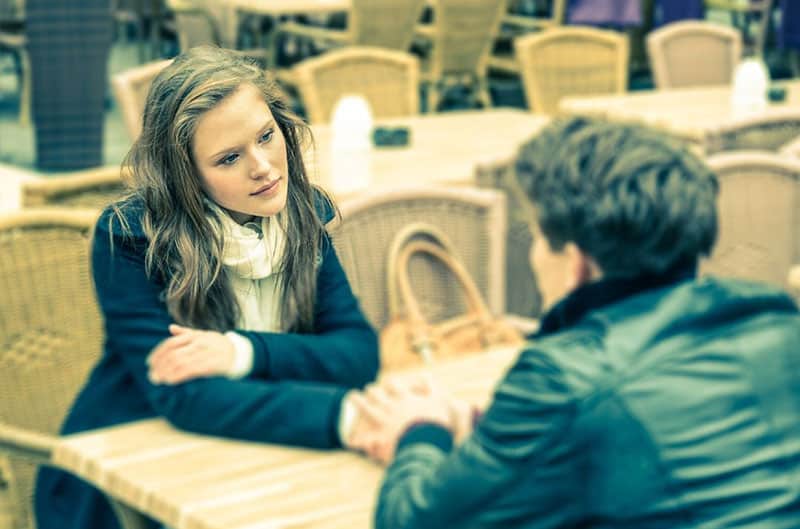 woman holding man's hand on a table inside a restaurant