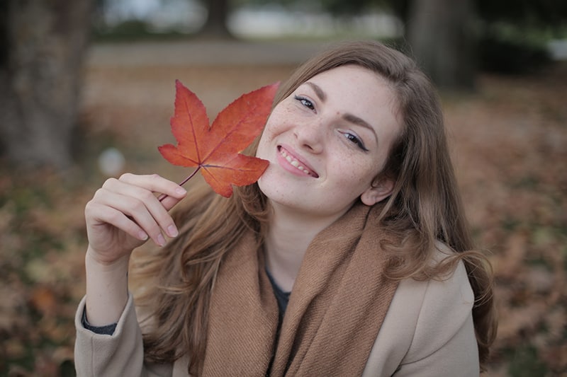 woman holding red leaf near her face