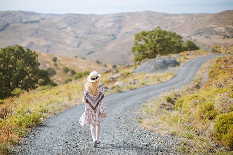 mulher de vestido a caminhar numa estrada de gravilha