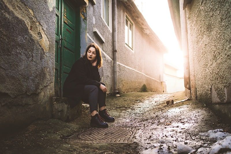 woman in black jacket sitting on doorway
