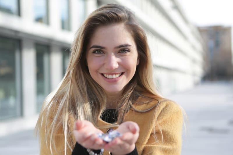 woman in brown sweater smiling carrying a blurred image of something in her hand