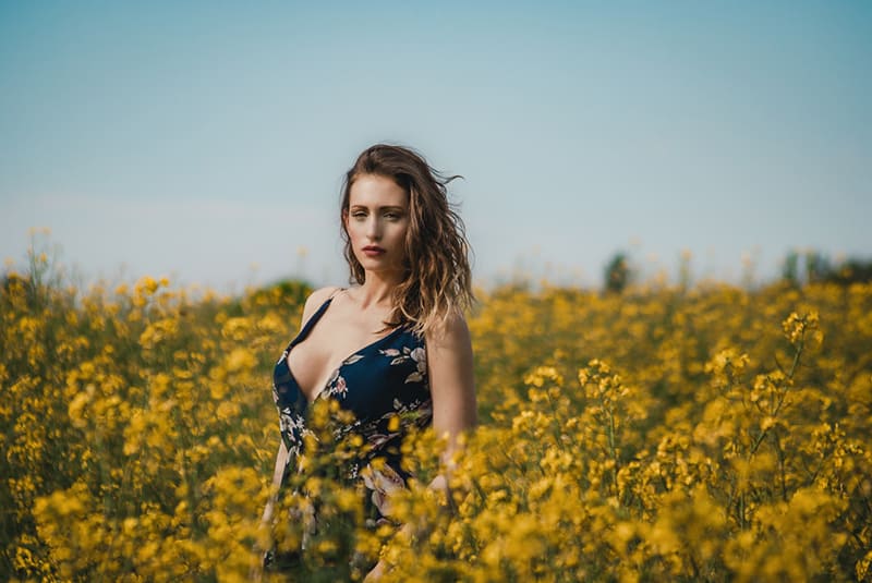 mujer con vestido floral de pie en un campo de flores
