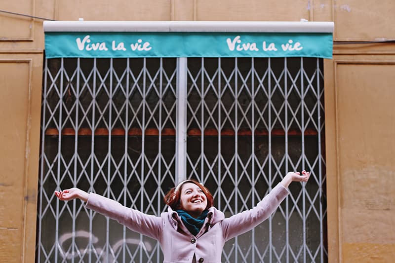 woman in front of scissor gate raising hands