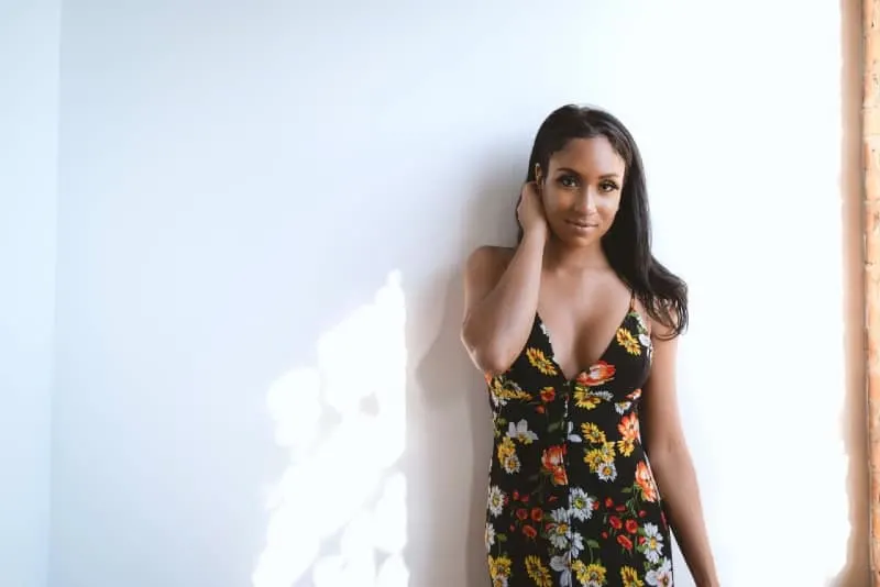 woman in black floral sleeveless dress leaning on wall