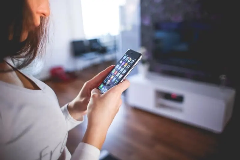woman wearing white v neck shirt looking at phone