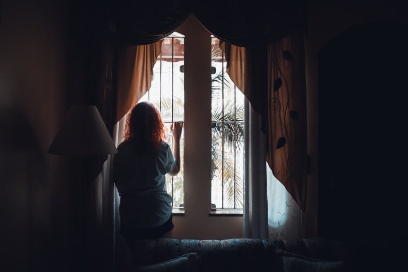 woman standing near window and looking through window