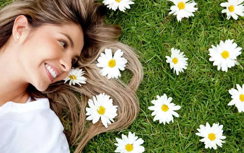 Happy blonde woman lying in a flower garden