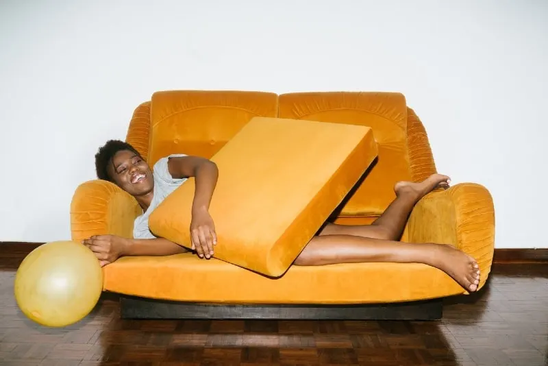 smiling woman lying on orange sofa