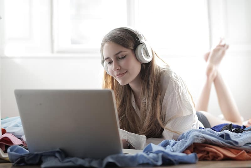 woman lying on the bed while using laptop