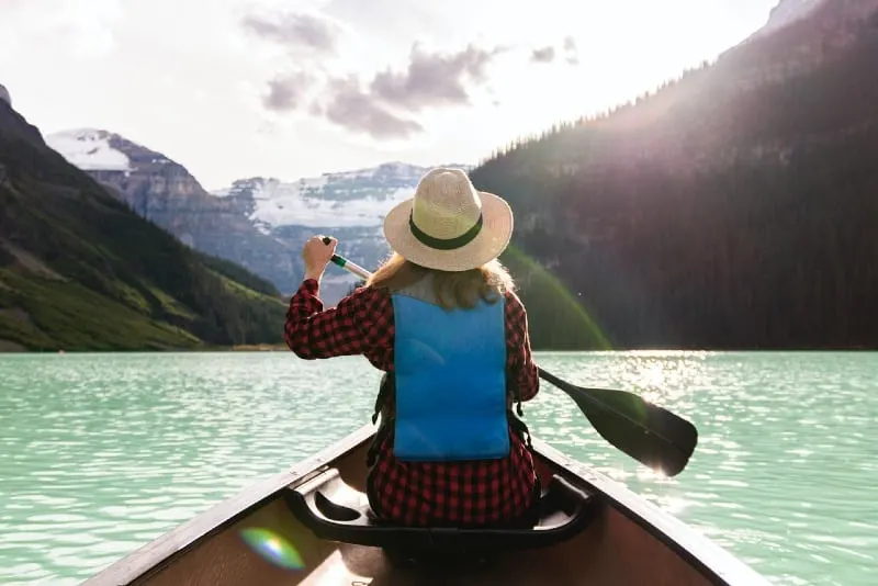 woman with hat paddling a boat in the lake