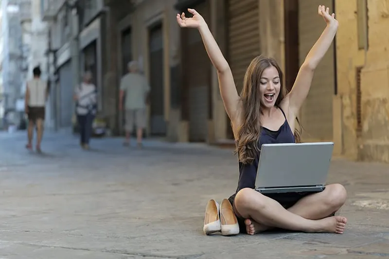 woman raising her hands up while sitting on the floor