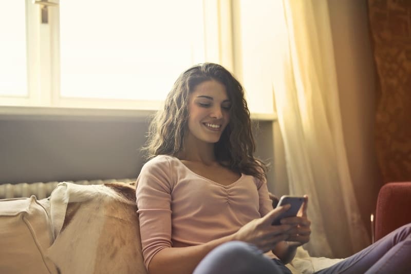 woman sitting on bed and looking at phone